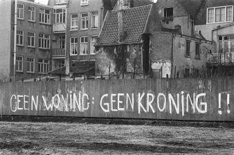 Foto met de tekst "Geen woning, geen kroning" op schutting Haarlemmer Houttuinen in Amsterdam, 26 maart 1980.