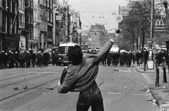 Foto van stenengooier op het Rokin in Amsterdam tegenover de Mobiele Eenheid, 30 april 1980.